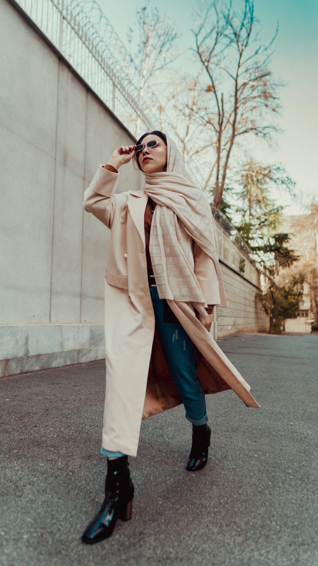 a woman in a trench coat is talking on a cell phone
