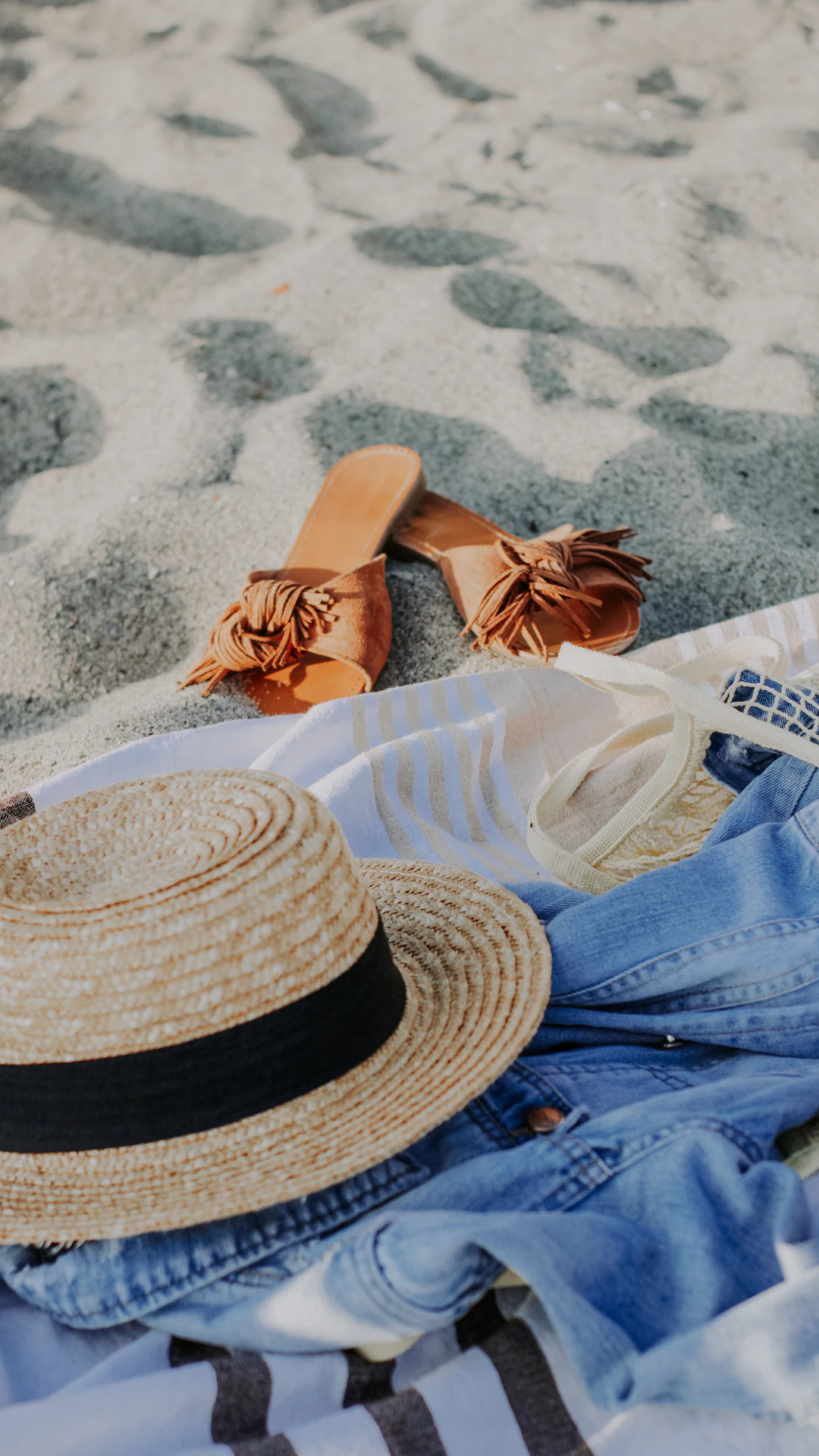a pair of sandals and a hat laying on a towel